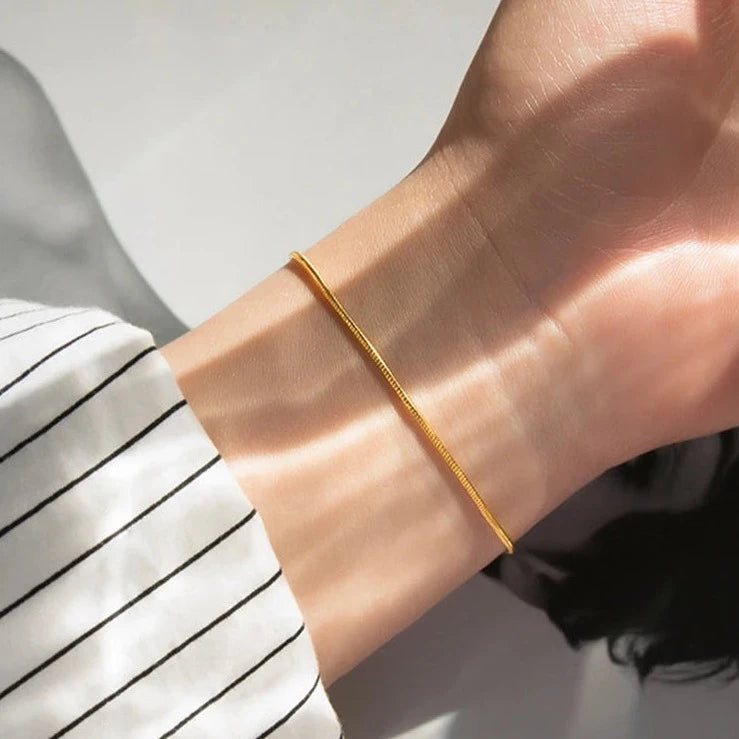 Carina – Gouden armband met een glanzende platina structuur.