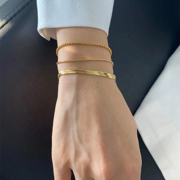 Carina – Gouden armband met een glanzende platina structuur.
