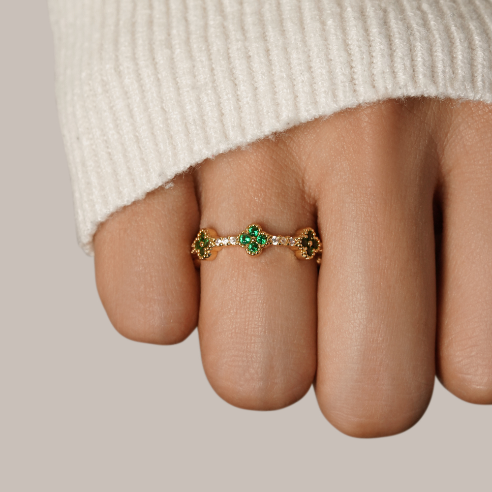 Annika – Gouden ring met bloemige details en smaragdinslag.